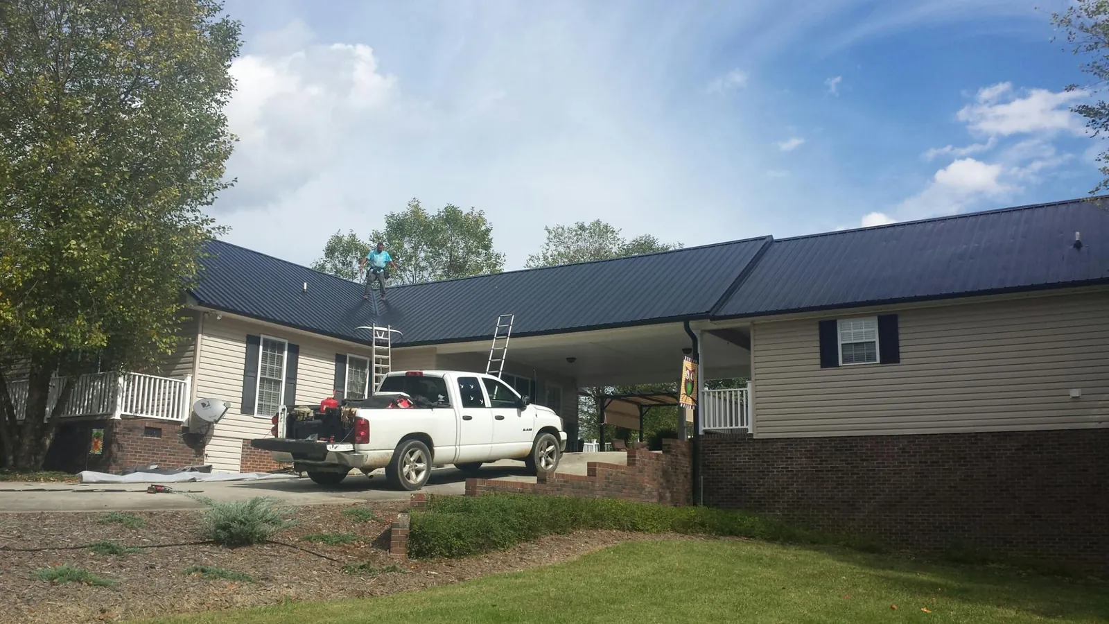 Black metal roof over a home and attached breezeway with ladders set in Russell